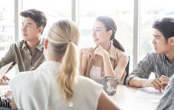 Attractive asian businesswoman and businessman listening to teacher or mentor coach speaking to young people teaching audience at training seminar, group mixed race persons in meeting room at office. - Photo, Image