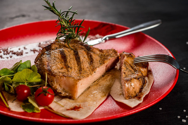 Tasty fresh grilled marble steak in a red plate - Foto, Bild
