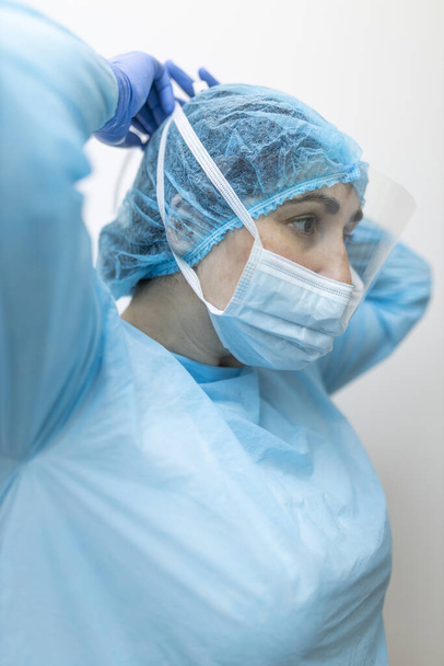 fiatal ápolónő köti a légzőkészüléket védőruházattal - Fotó, kép