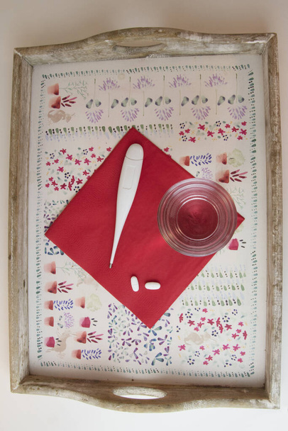 Δίσκος με γυαλί νερού, χάπια και θερμόμετρο, κόκκινο και άσπρο - Φωτογραφία, εικόνα