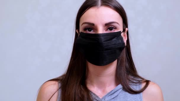 La paziente con una maschera protettiva nera guarda la telecamera. Concetto di igiene. prevenire la diffusione di germi e batteri ed evitare l'infezione con il virus della corona
 - Filmati, video