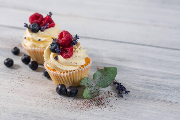 Sweet dessert cupcakes with fruits on the white wooden background - Фото, зображення