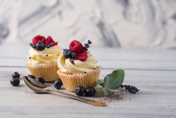 Sweet dessert cupcakes with fruits on the white wooden background - Zdjęcie, obraz