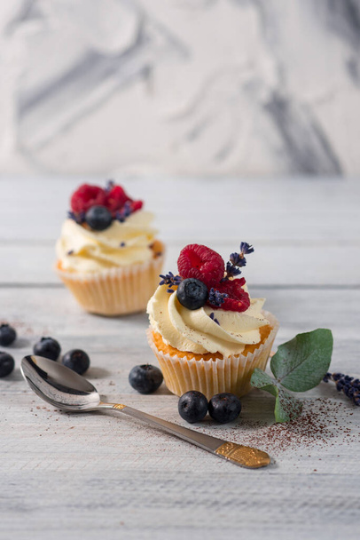 Sweet dessert cupcakes with fruits on the white wooden background - Фото, изображение
