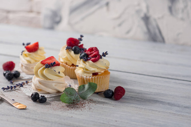 Süße Dessert-Cupcakes mit Früchten auf weißem Holzhintergrund - Foto, Bild