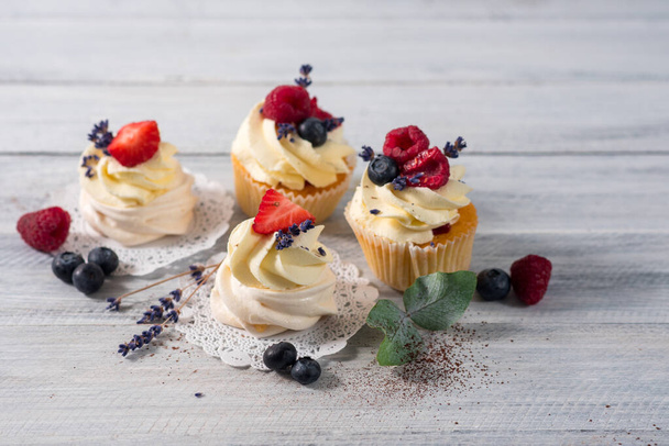 Sweet dessert cupcakes with fruits on the white wooden background - Foto, afbeelding