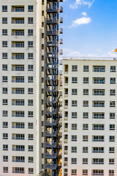 Vertical photo of apartment building exterior with metal emergency stairs - 写真・画像