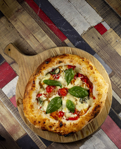 Italian Pizza in chopping board on a wooden table - Photo, Image