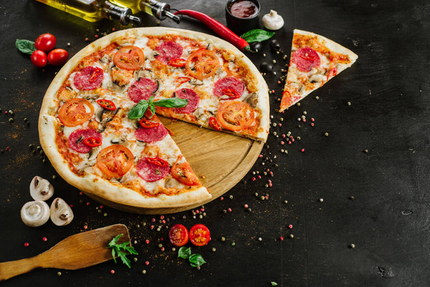Tasty pizza with salami and cheese on black background - Photo, image