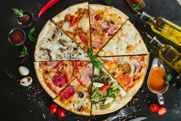 Different pieces of pizza put in one big pizza on black - Foto, Imagen