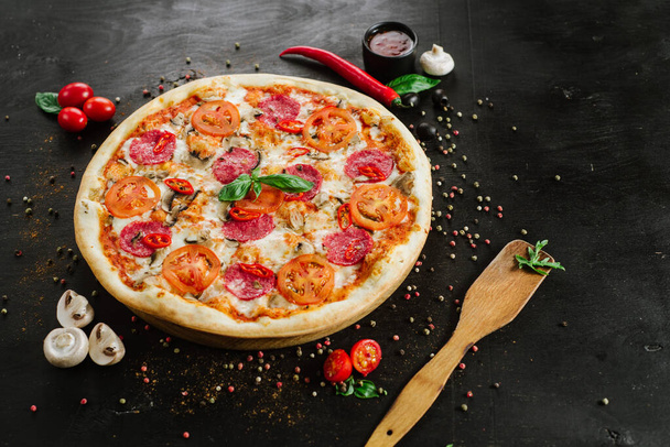 Sabrosa pizza con salami y queso sobre fondo negro
 - Foto, Imagen