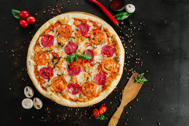 Tasty pizza with salami and cheese on black background - Zdjęcie, obraz