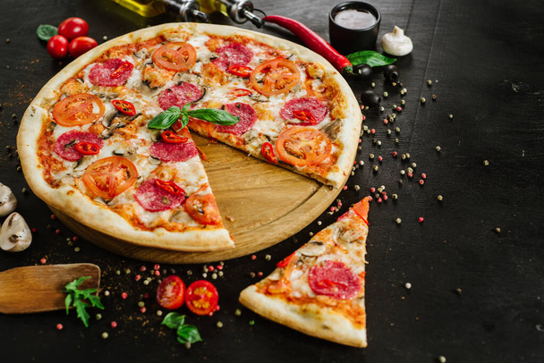 Tasty pizza with salami and cheese on black background - Photo, image