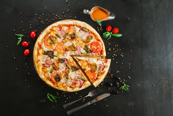 Tasty meat pizza with various ingredients on black background - Fotó, kép