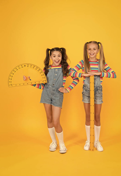School club. School children with measuring instruments. Little girls ready geometry lesson. Cute schoolgirls holding protractor and ruler for school lesson. Studying measurement. Interesting task - Foto, Imagen