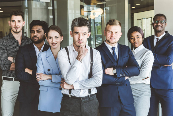A team of young businessmen stand shoulder to shoulder, working and communicating together in an office. Corporate businessteam and manager in a meeting. - Фото, зображення