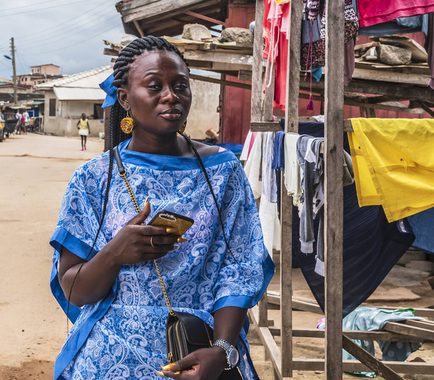Ghana femme en robe bleue se tient dans une rue dans un village de pêcheurs situé au Ghana
. - Photo, image