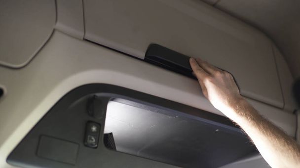 Close up of a cabin of modern truck with glove box, transportation concept. Scene. Male hand closing glove compartment and putting his wallet on the shelf. - Photo, Image