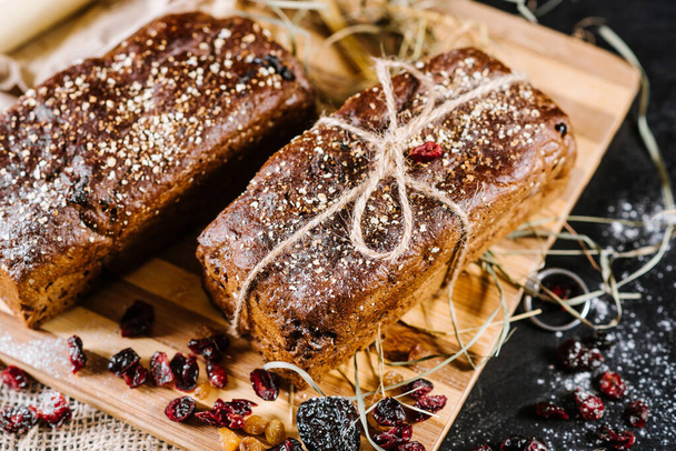 sweet and tasty bread and wheat on black wooden background - Photo, image