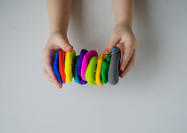 Ręce dziecka bawiące się kolorową gliną. Plastylina domowej roboty - Zdjęcie, obraz