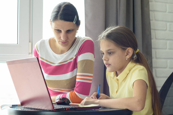 Мама і дочка вирішують домашнє завдання за допомогою онлайн дистанційного навчання - Фото, зображення