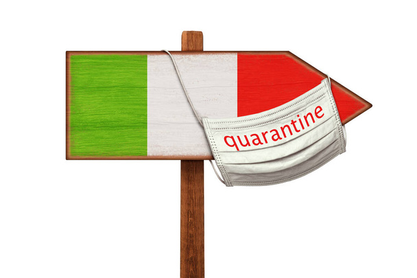 Quarantine during the COVID-19 coronavirus pandemic in Italy. Medical mask with the inscription QUARANTINE hangs on a sign pointer with the image of the flag of Italy. Anti-epidemic measures. - 写真・画像