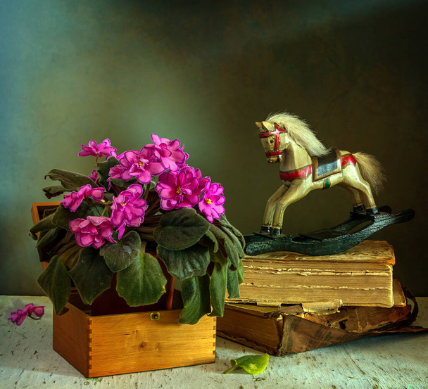 紫、木製のおもちゃの馬や古い本が咲くとまだ生活。ヴィンテージ。レトロ. - 写真・画像