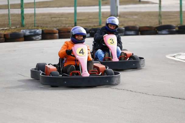 κορίτσι οδηγεί Go-kart αυτοκίνητο με ταχύτητα σε μια πίστα αγώνων παιδική χαρά. Go kart είναι ένα δημοφιλές σπορ αυτοκινήτων αναψυχής. - Φωτογραφία, εικόνα