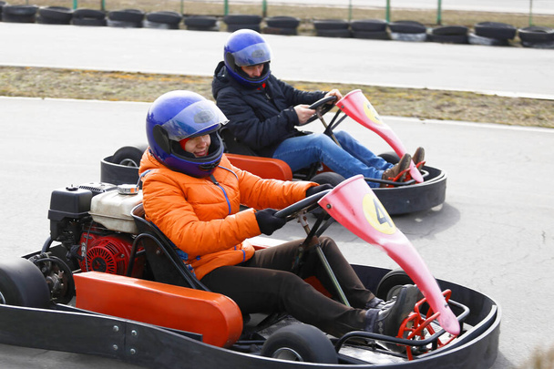 κορίτσι οδηγεί Go-kart αυτοκίνητο με ταχύτητα σε μια πίστα αγώνων παιδική χαρά. Go kart είναι ένα δημοφιλές σπορ αυτοκινήτων αναψυχής. - Φωτογραφία, εικόνα
