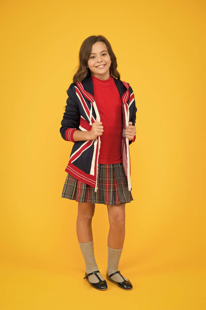 Learn english language. British accent. Great Britain flag. Small girl school uniform. English student. Education and upbringing. Culture and customs. Language school. English kid yellow background - Fotoğraf, Görsel