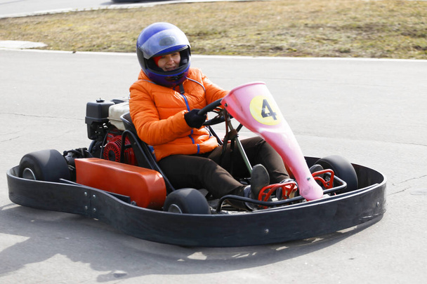 A lány gokart autót vezet sebességgel egy játszótéri versenypályán. Go Kart egy népszerű szabadidős motoros sport. - Fotó, kép