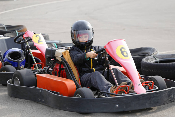 chico está conduciendo Go-kart coche con velocidad en una pista de carreras de juegos infantiles. El karting es un deporte de motor de ocio popular
. - Foto, imagen