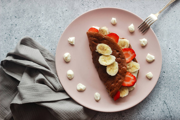 Delicious banana oatmeal pancake on a plate. Oatmeal pancake with cream cheese, banana and strawberries - Foto, afbeelding