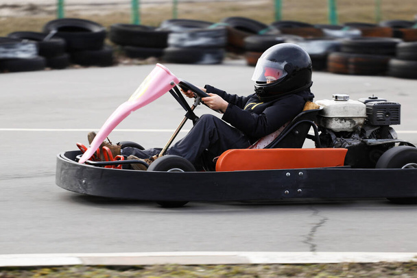 A fiú száguldó gokart autót vezet egy játszótéri versenypályán. Go Kart egy népszerű szabadidős motoros sport. - Fotó, kép
