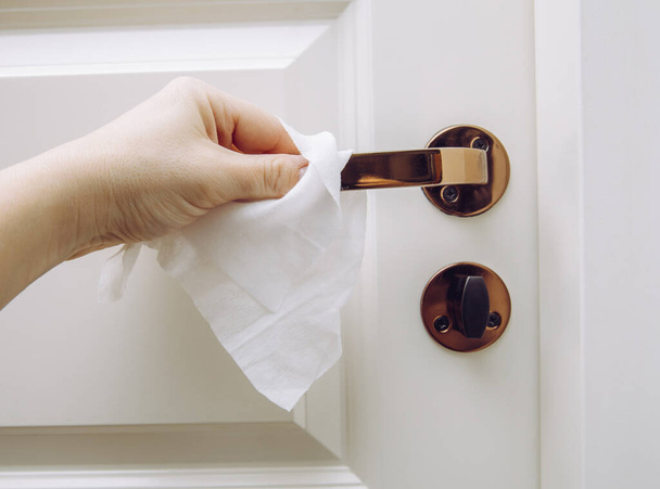 Lähikuva naisen käsi käyttäen antibakteerinen märkä pyyhe desinfiointiin kotihuoneen oven linkki
. - Valokuva, kuva