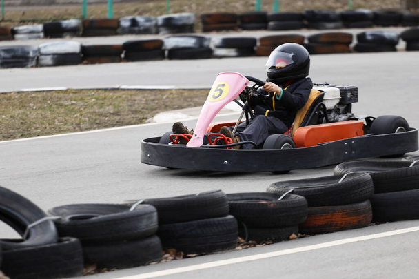 chico está conduciendo Go-kart coche con velocidad en una pista de carreras de juegos infantiles. El karting es un deporte de motor de ocio popular
. - Foto, Imagen