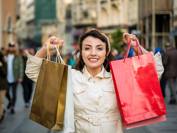 Schöne attraktive junge Mädchen in modischen Kleidern hält Einkaufstüten nach dem Einkaufen, während sie auf der Straße spazieren. Glückliche Frau mit Einkaufstüten. Shopping, Lifestylekonzept - Foto, Bild