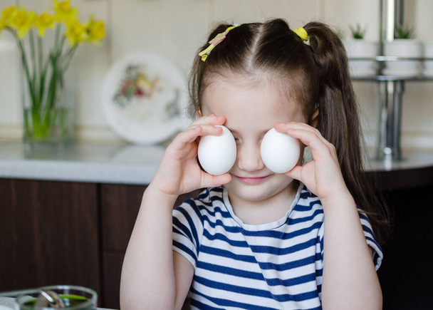 イースターのコンセプト。イースターの準備だ。小さな子供の女の子はイースターのために卵を着色しています - 写真・画像