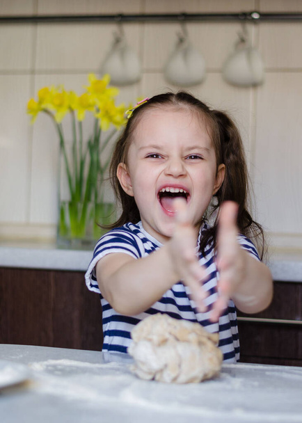 Easter concept. happy cute child girl is are preparing the Easter cakes, bake cookies in the kitchen. Portrait of happy funny kid in the Easter - Photo, Image