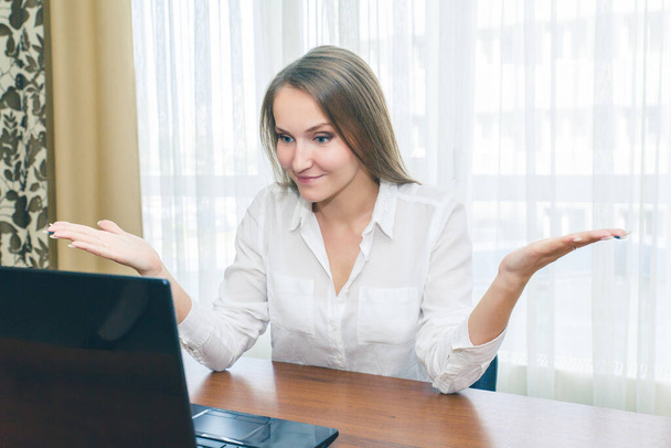 Very surprised and dissatisfied girl expresses emotion looking at the laptop. Girl at work in the office with a surprised look. - Foto, Imagem