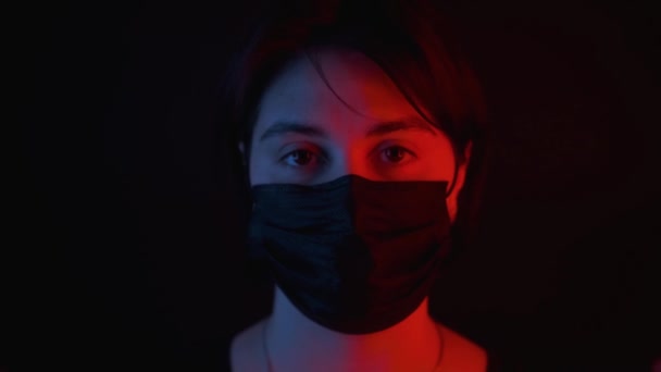 Caucasian girl in black medical mask,red and blue neon light on face - Séquence, vidéo