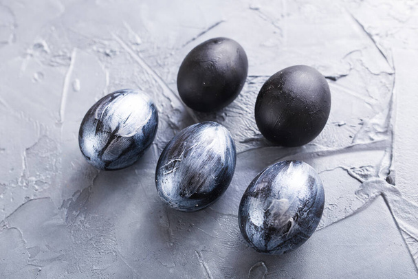Feste, tradizioni e concetti pasquali: uova pasquali scure ed eleganti su sfondo grigio
. - Foto, immagini