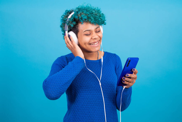 fiatal lány mobiltelefon és fejhallgató elszigetelt színes háttér - Fotó, kép