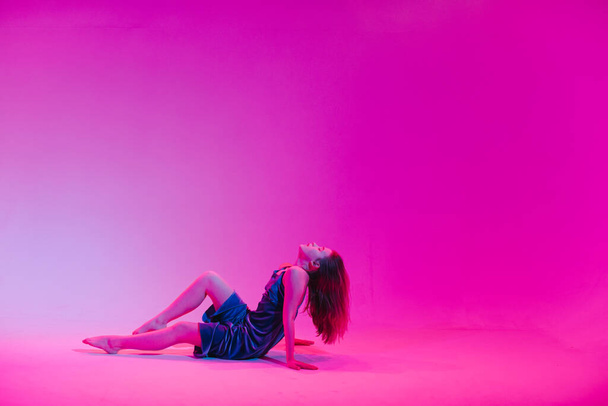 Giovane ragazza elegante che balla in studio su uno sfondo colorato al neon. Disegno poster dj musica
. - Foto, immagini
