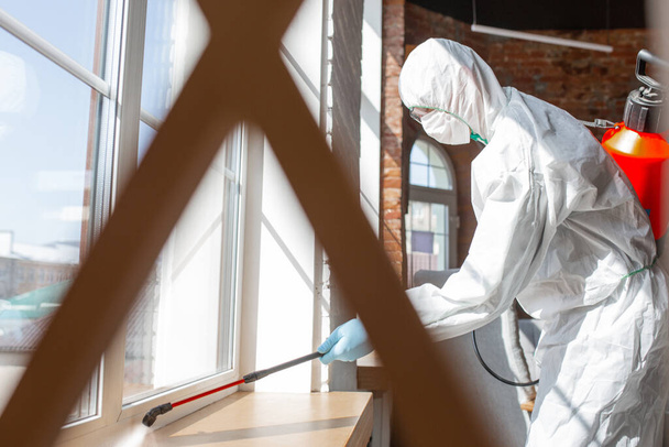 Pandemia di Coronavirus. Un disinfettante in tuta protettiva e maschera spruzza disinfettanti in casa o in ufficio
 - Foto, immagini