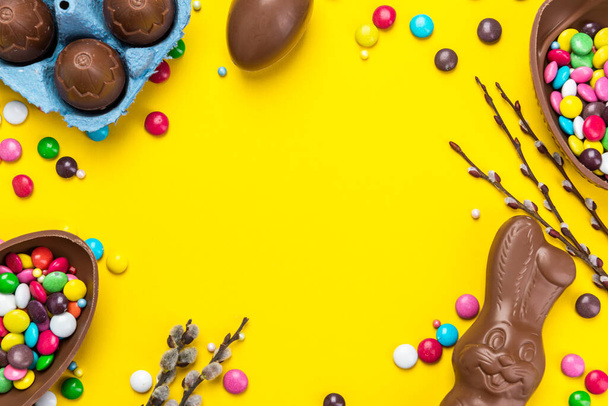 Renkli Paskalya Bahçesi. Sarı Arkaplanda Çikolatalı Yumurta ve Şeker. Düz Dizayn Üzerine Alan Kopyala. - Fotoğraf, Görsel