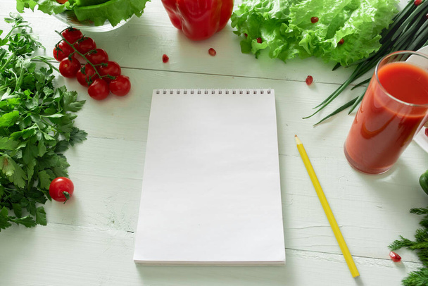 Cuaderno para llevar un diario de pérdida de peso en el fondo de las verduras. Elaboración de una dieta individual
. - Foto, imagen