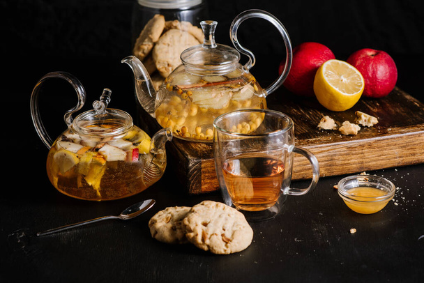 Glass teapots with fruit tea in composition on black background - 写真・画像