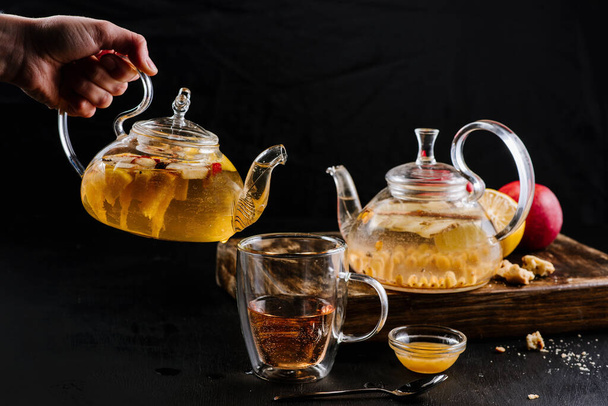 Glass teapots with fruit tea in composition on black background - Фото, зображення