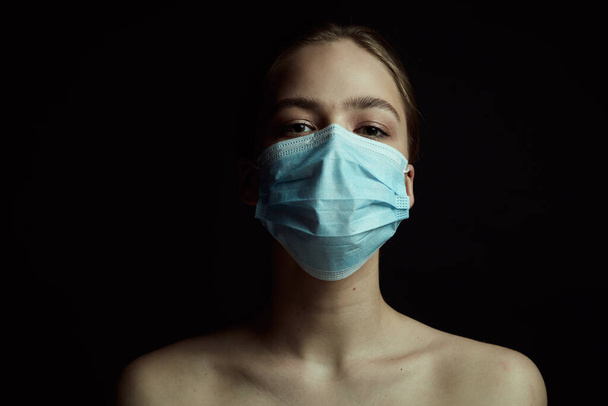 Dramatic light illustration of coronavirus epidemic. Girl with protective mask. Black background. Concept of quarantine. - Fotoğraf, Görsel